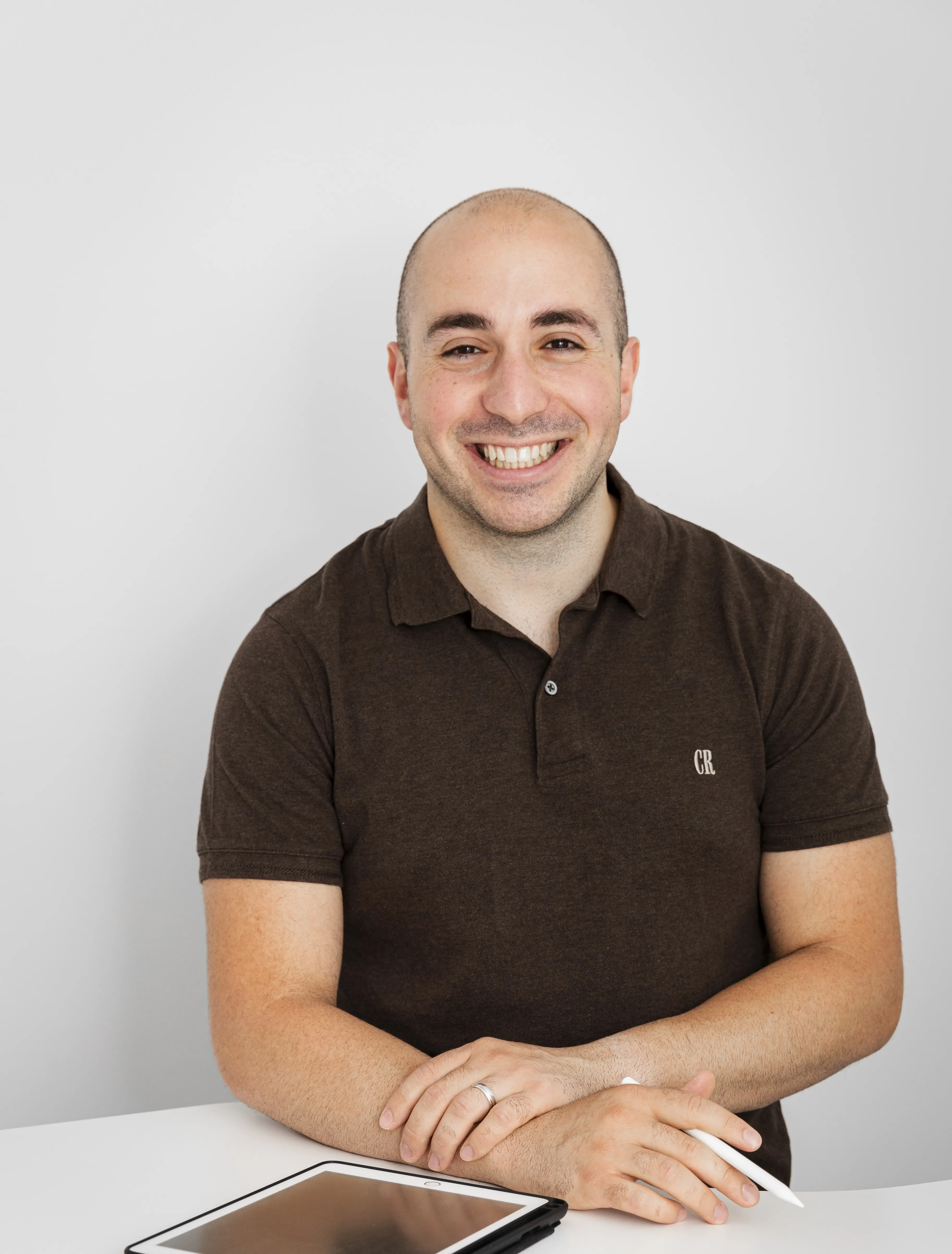 Robert Daniele in a t-shirt smiling at the camera with an ipad in front of him.