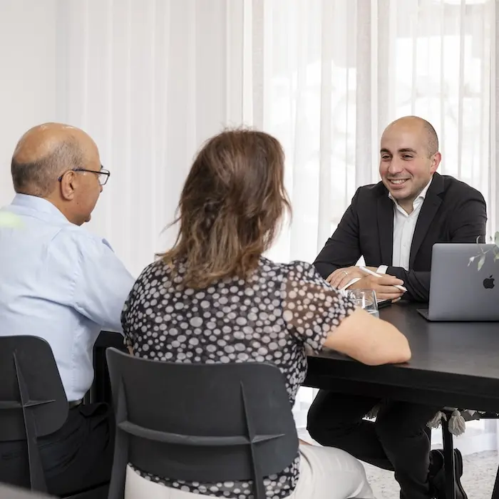 Robert Daniele speaking with a retired couple in his office.